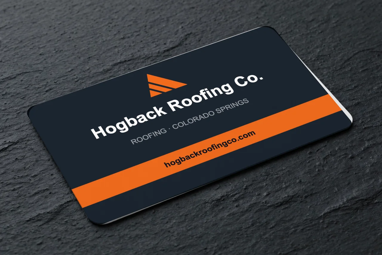 A Hogback Roofing Co. business card on dark slate: the logo mark and name over an orange band with the website