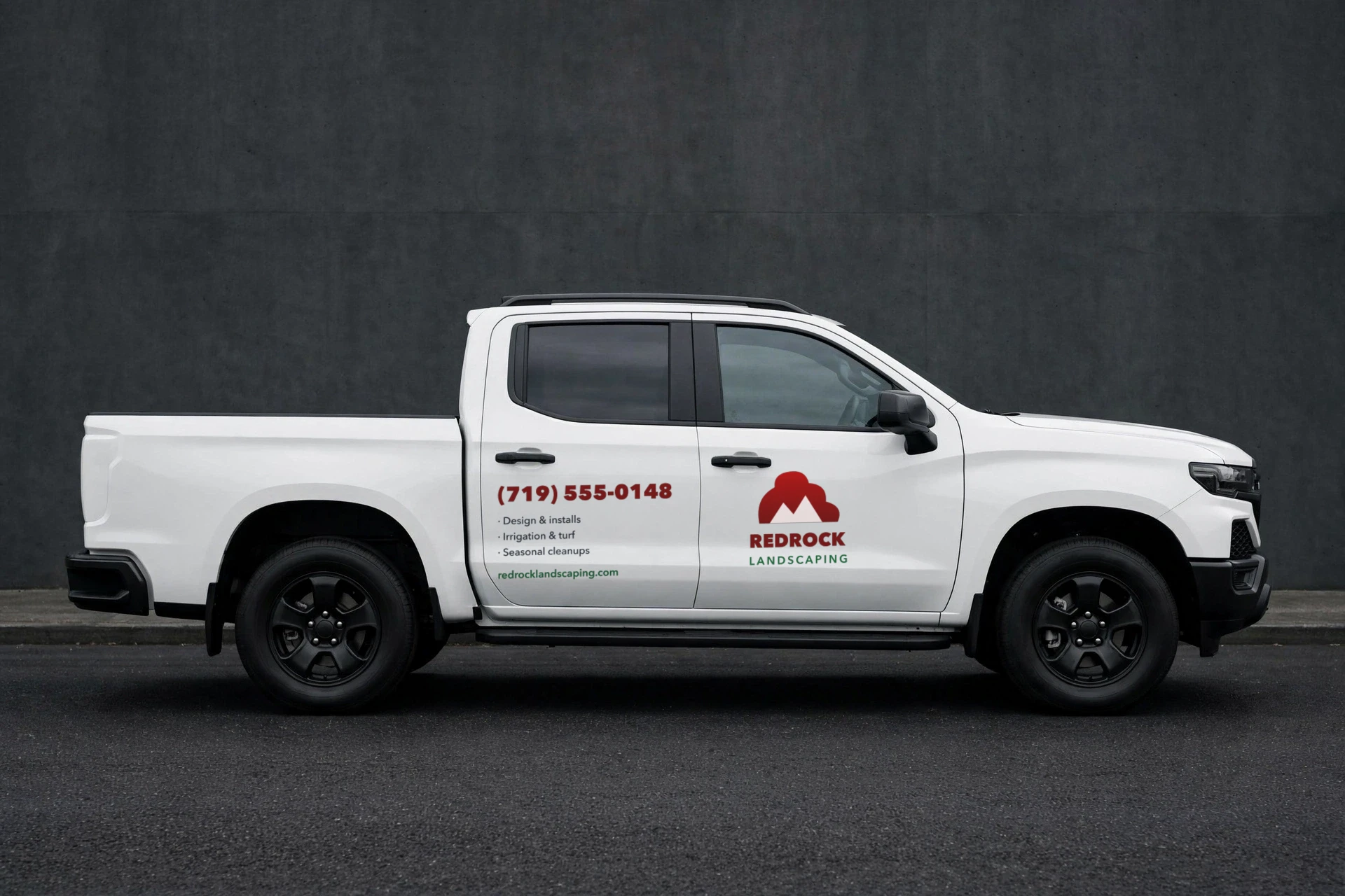 White pickup with a fictional landscaping decal set: door logo, phone number and services