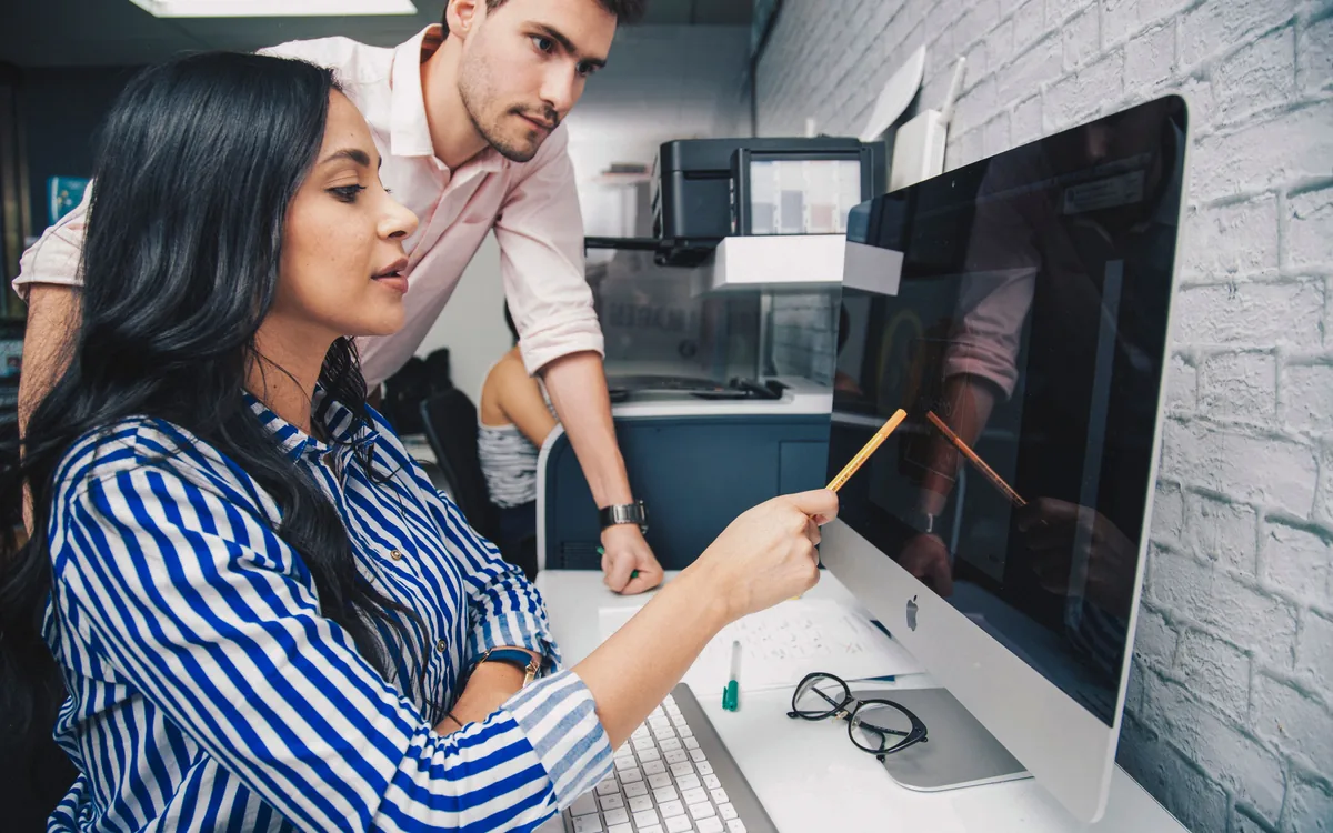 Two people reviewing a design together on a screen before it goes to production