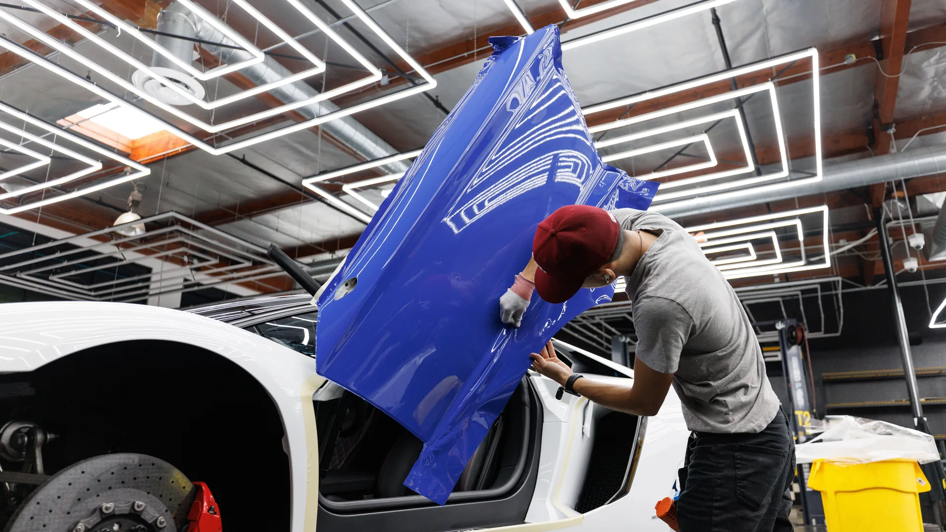 An installer laying vinyl onto a van panel in a wrap shop