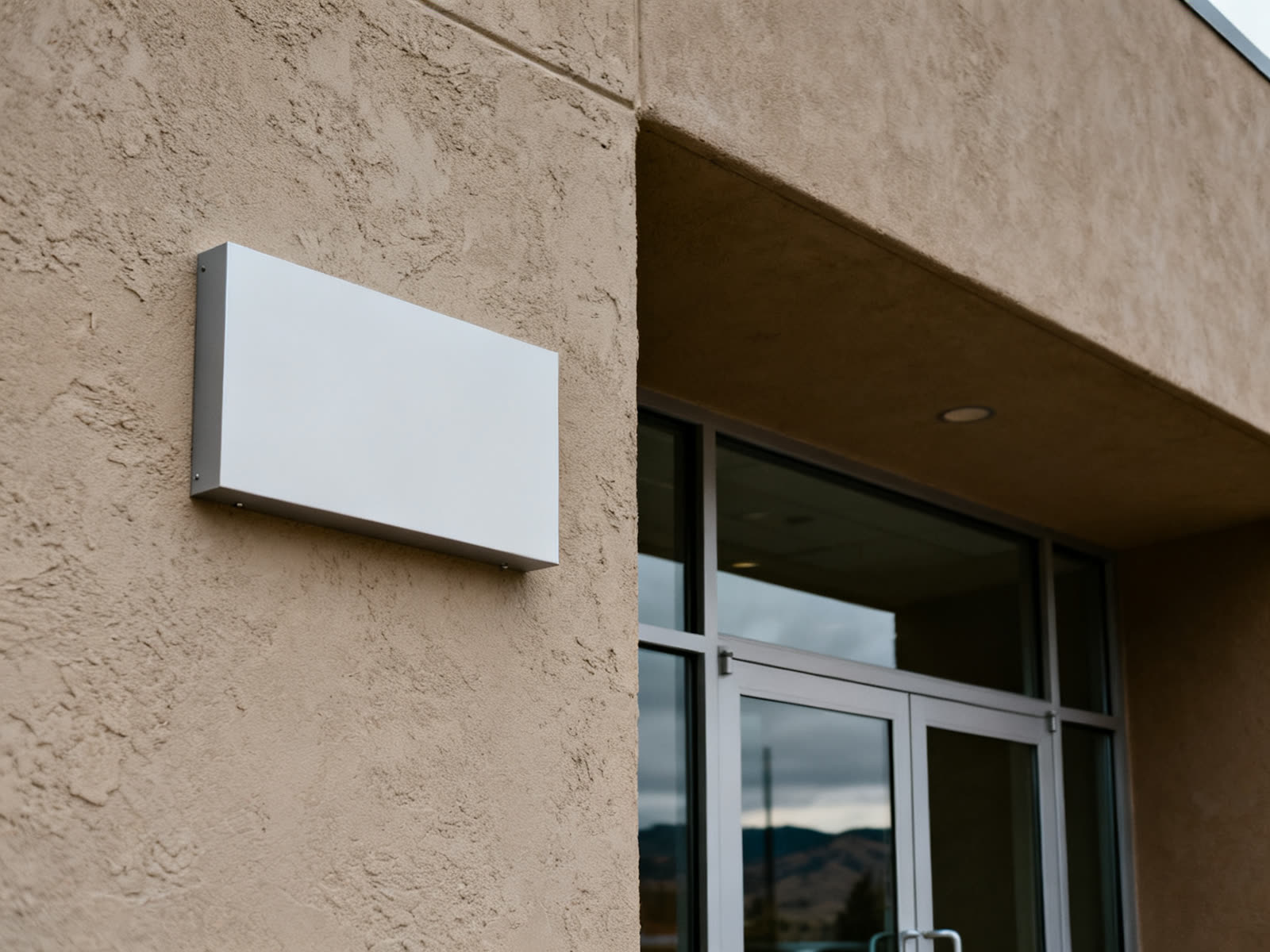 Blank rigid panel standoff-mounted on a stucco wall beside an entrance