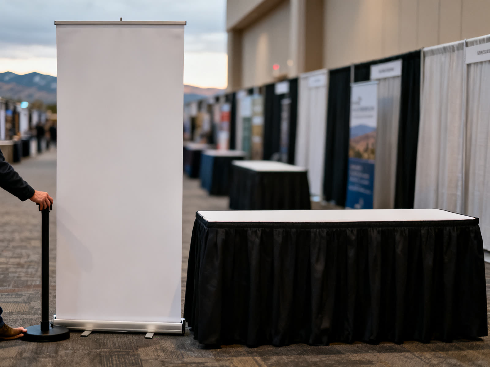 Retractable banner stand and fitted table throw in a convention aisle