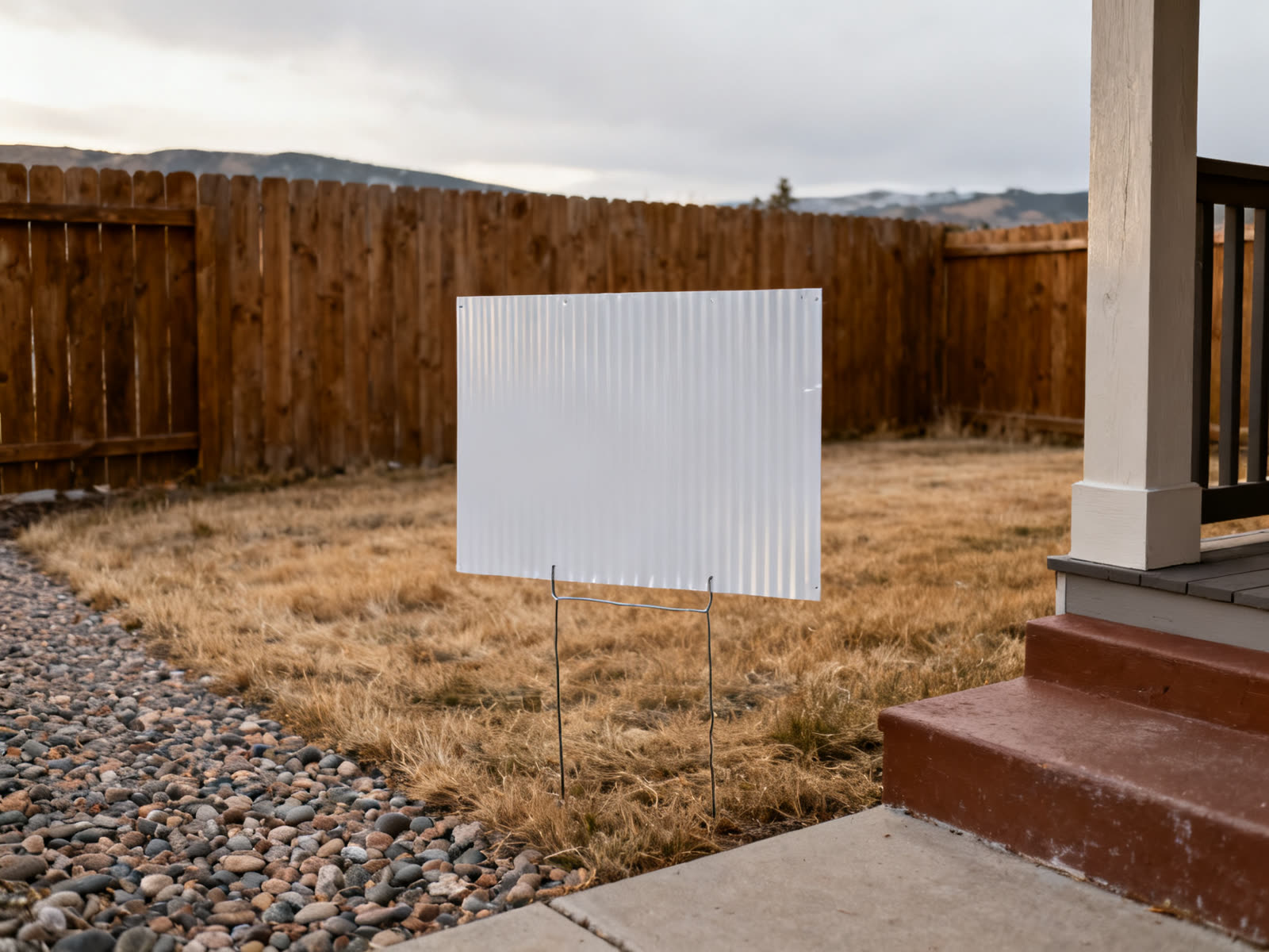 Corrugated yard sign on wire stakes in a dry front lawn