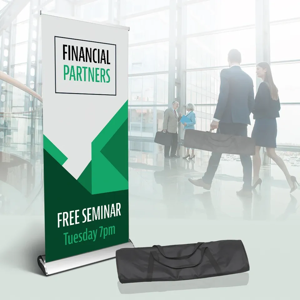 A retractable banner stand set up in a bright lobby, its carry bag beside it