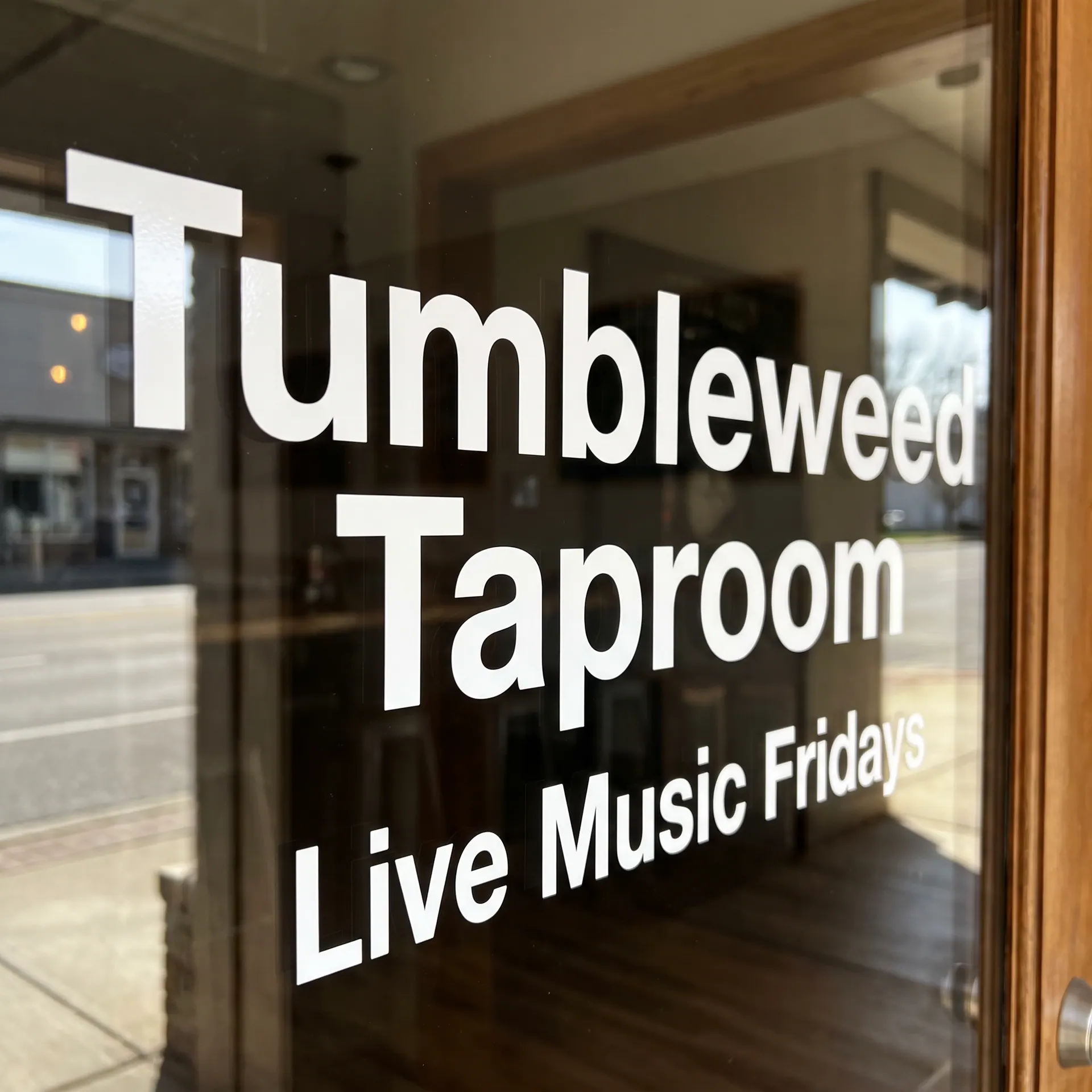 Weeded solid white cut vinyl lettering with no background, crisp letter edges, 24″ × 8″, shown with a sample design: applied to the glass door of a small shop